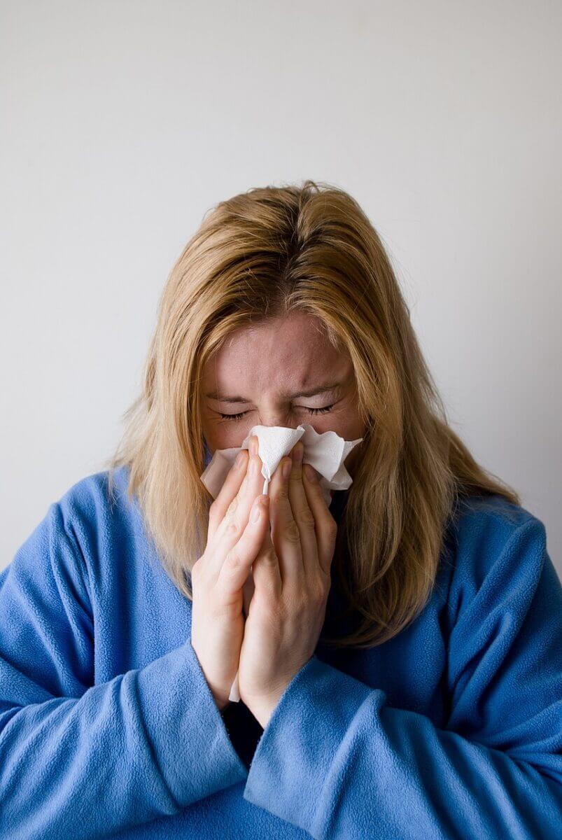 woman having cat allergy blowing her nose